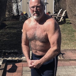 Man with a beard and glasses posing outdoors on a patio.