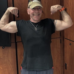 Man flexing his muscles in front of wooden lockers