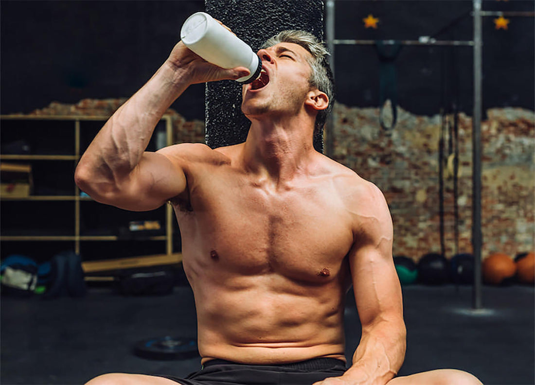 Fit white man sitting in a gym drinking a pre-workout