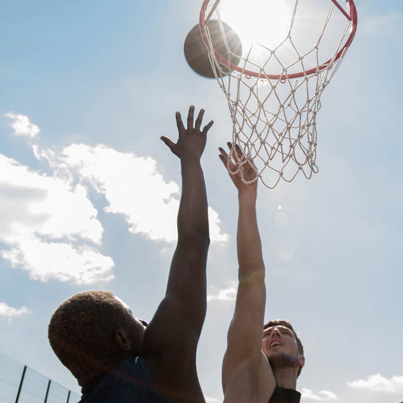 Two basketball players in action with a clear sky background