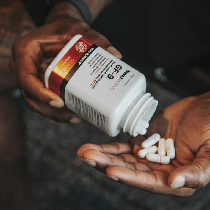 Person holding a GF-9 supplement bottle with pills in their hand