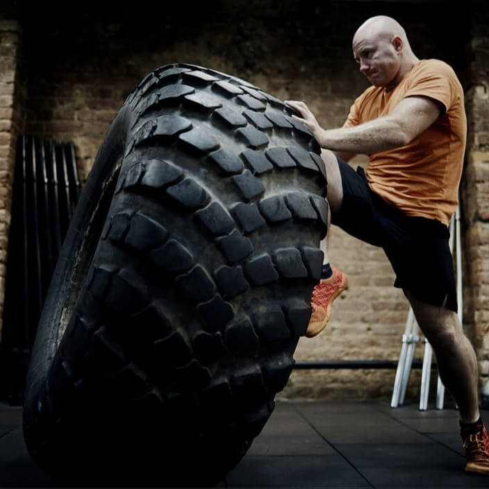 Man lifting a large tire in a gym setting
