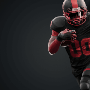 An American football player wearing a black and red uniform is running with the ball