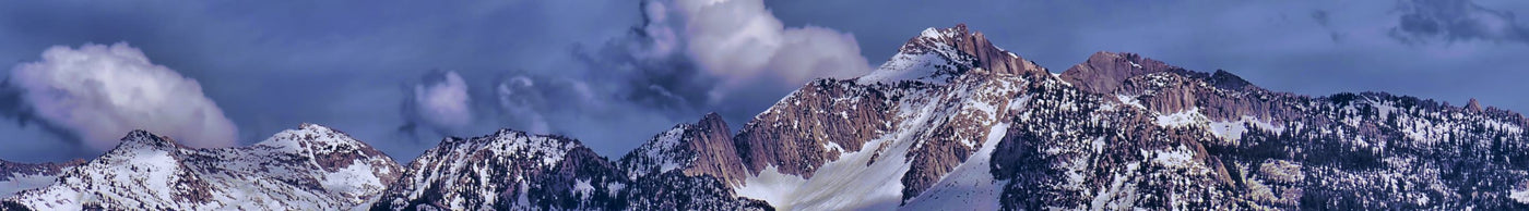 Snow-capped mountain peaks under a blue sky with scattered clouds
