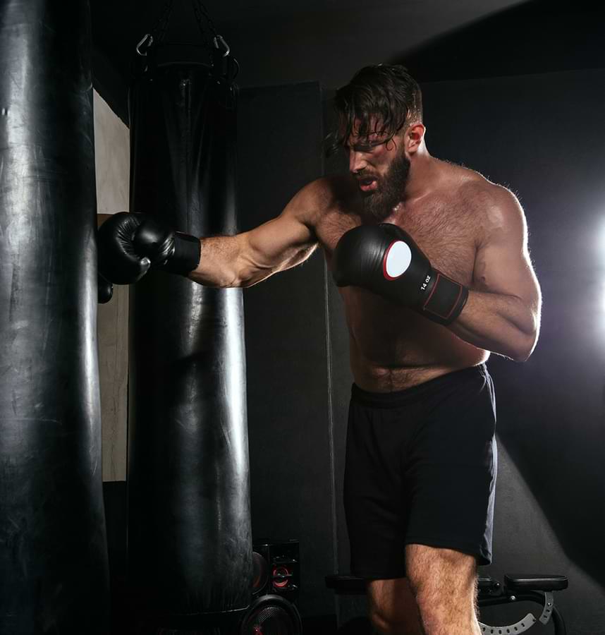 A muscular, bearded white man doing an intense boxing workout