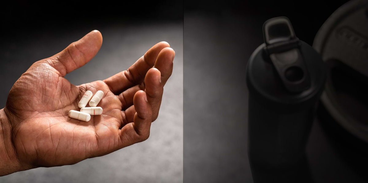 Closeup shot of a hand holding four GF-9 capsules with shaker bottle and weights nearby.