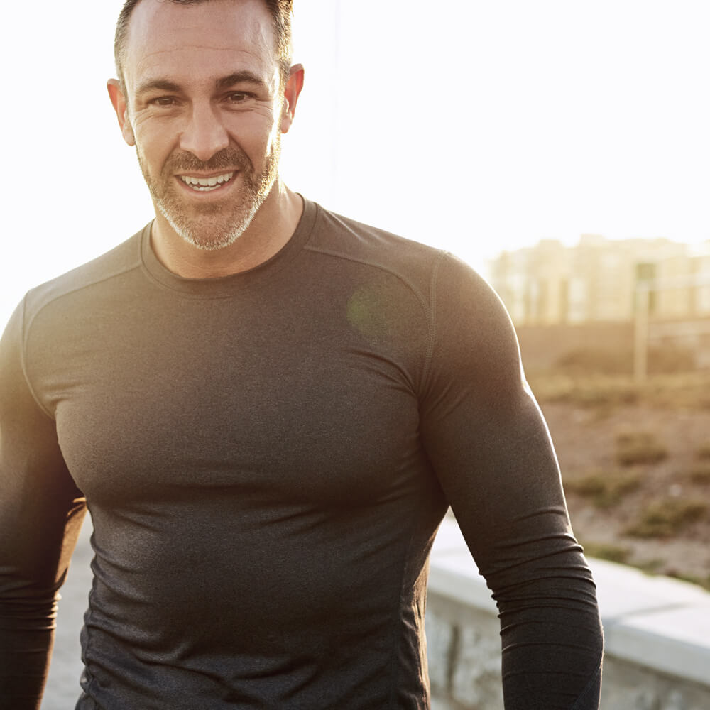 Man wearing a dark long-sleeve shirt outdoors with a blurred background