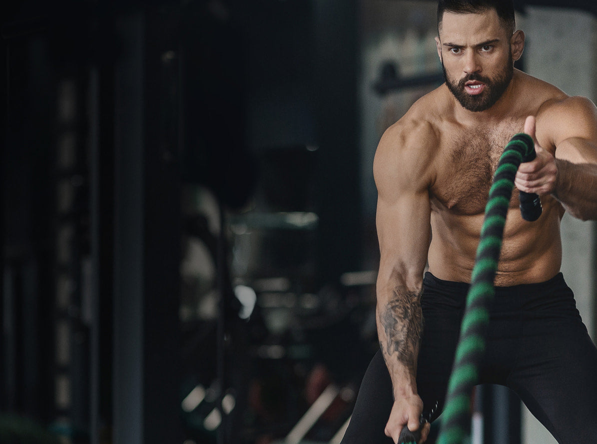 Muscular man exercising with ropes in a gym setting