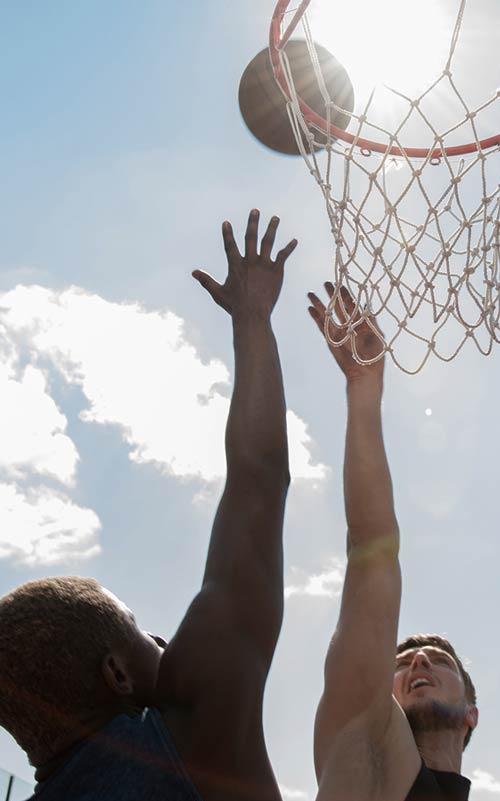 Two people playing basketball with a clear sky in the background