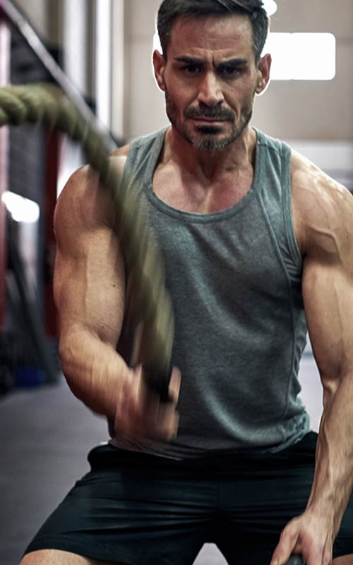Man exercising with battle ropes in a gym setting